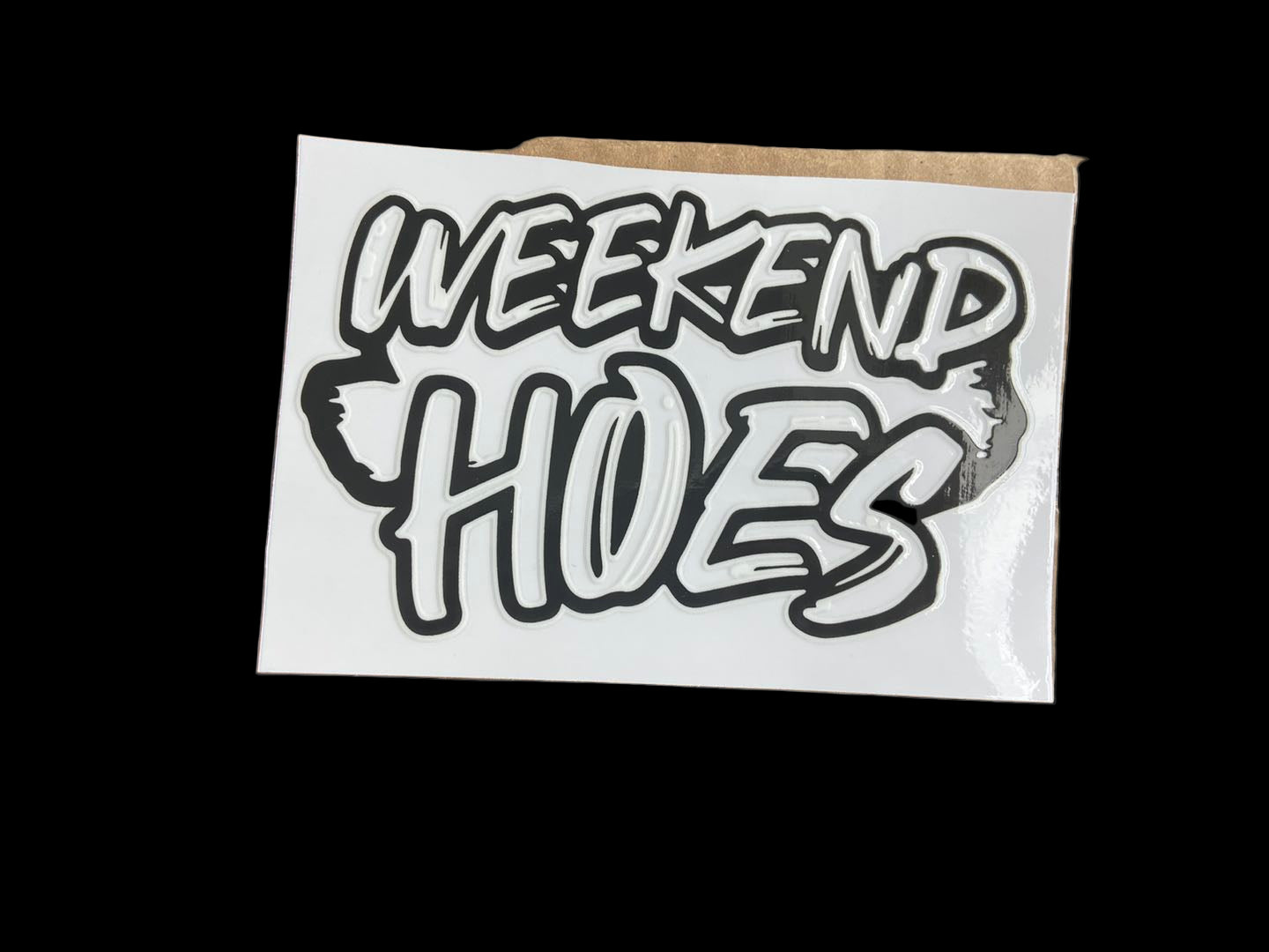 Cardboard box with a 'Weekend Hoes' sticker on a reflective surface
